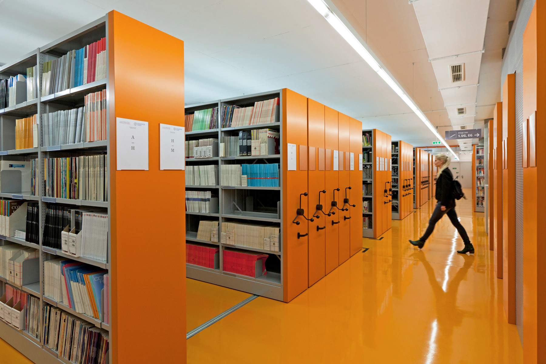 rayonnages roulants dans une bibliothèque avec des parois oranges, adaptées au sol orange de la pièce